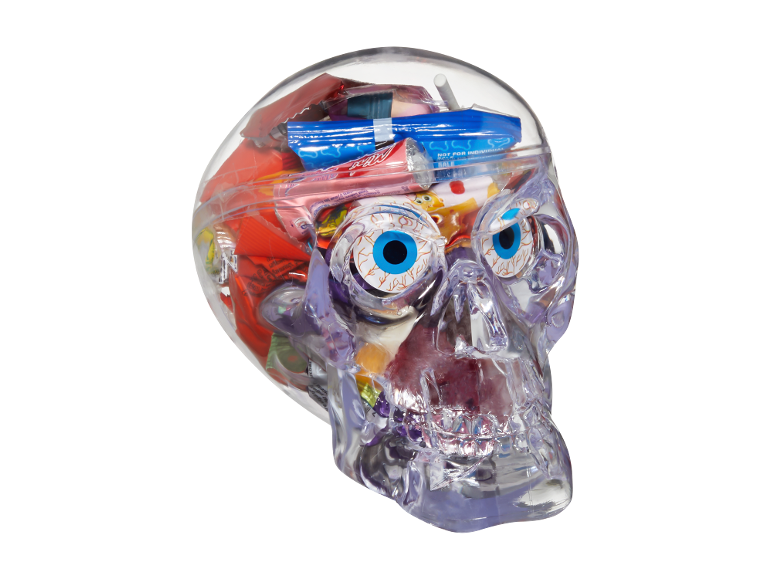 Clear skull filled with assorted Halloween candy, including gummy eyeballs and wrapped sweets.