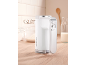 White hand mixer on a wooden countertop with kitchen utensils in the background.