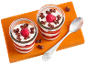 Two glass desserts with raspberries and bone-shaped cereals on a wooden board.