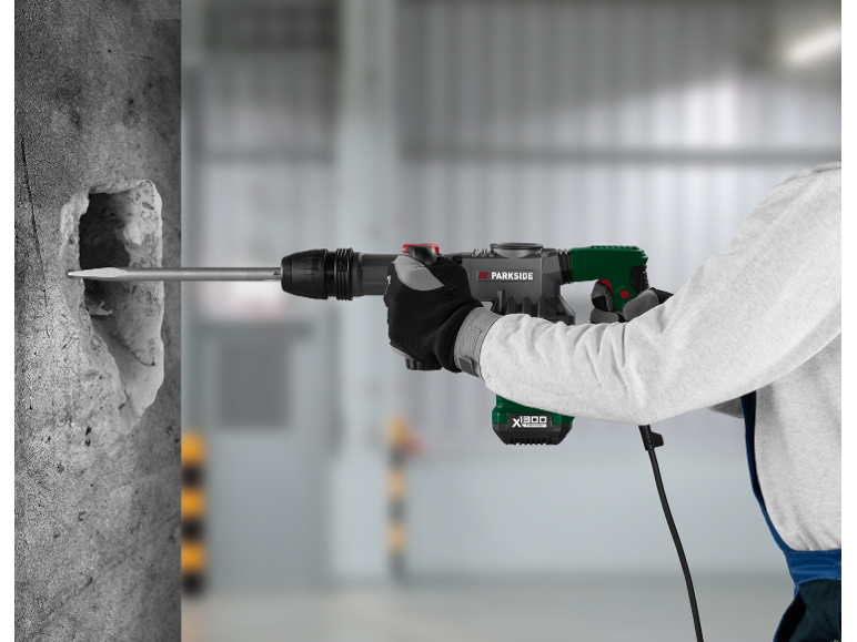 Man using a hammer drill to break down a concrete wall.