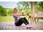 Woman in purple t-shirt and black leggings exercising with dumbbells on a yoga mat.