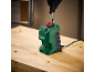 Green drill bit sharpener with a black gloved hand inserting a drill bit on a wooden table.
