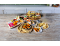 A wooden table with a variety of Asian dishes, including breaded prawns, dumplings, and spring rolls.