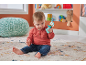Baby sitting on a rug, playing with a blue and colorful rattle.