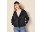 Woman in black pea coat, grey t-shirt, blue jeans, and black beanie.