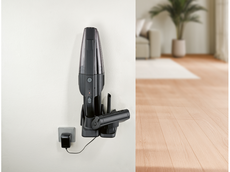 Black cordless handheld vacuum cleaner mounted on wall, charging, in a modern interior.