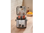 Deep fryer with chicken wings and french fries on a wooden countertop.