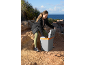 Woman opening a portable electric cool box on a rocky coastal path