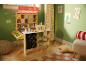 Wooden toy market stall with striped awning, products, and basket in a green room.