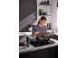 Woman cooking a meal on an induction hob with two pans, meat in one, vegetables in the other.