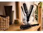Hairbrushes and combs in a glass, with beauty products and a basket on a wooden shelf.