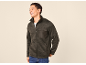 Smiling man wearing a grey fleece jacket with a chest pocket and a white t-shirt.