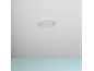 White smoke detector housing mounted on a light ceiling above a light blue wall.