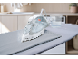Steam iron on ironing board with water measuring cup.