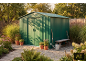 Green garden shed with tools, bench, and potted plants in a sunny garden.