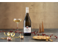 Sparkling wine bottle with a glass, festive decorations, and nuts.