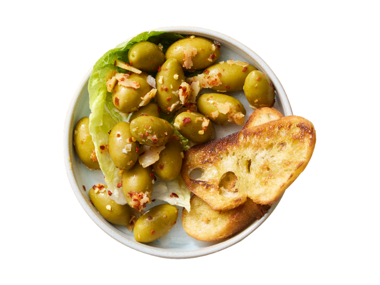 Marinated green olives with chili and garlic, served with toasted bread slices.