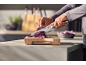 Hands slicing red cabbage on a wooden cutting board in a modern kitchen.