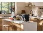 Black air fryer in a modern kitchen with a salad and a vegetable chopper.