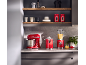 Red stand mixer, juicer, and blender in a modern kitchen with shelves.