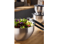 Stainless steel mixing bowls with fresh salad and kitchen tongs on a wooden counter.
