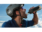 Cyclist in helmet and glasses drinking water from a bottle.