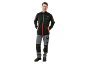 Man in black softshell jacket and grey work trousers with black details.
