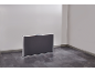 Foldable table in a closed position, standing upright against a white wall.