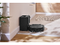 Black robot vacuum cleaner with charging station in a modern hallway with wood and tile flooring.