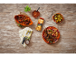 Chickpea dish with lamb chops, peppers, and sauce on a wooden table.