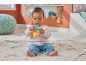 Baby sitting on a rug, playing with a colorful rattle.