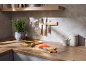 Modern kitchen with wooden countertop, knives on magnetic holder, herbs, and salmon.