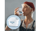 Woman drinking water with a Maxtra Pro water filter in the foreground.