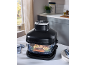 Black steamer with salmon and vegetables in a glass bowl on a kitchen table.