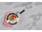 Frying pan with roasted tomatoes, zucchini, and mushrooms on a gray surface.
