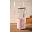 Pink blender with a glass jug and base, on a wooden countertop with light tiles in the background.