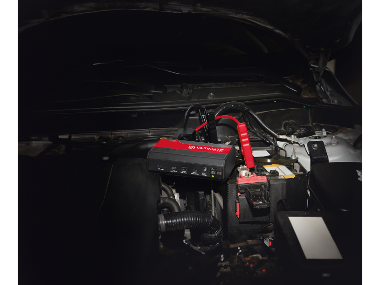 Car battery jump starter connected to a vehicle's battery.