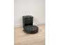 Black robot vacuum cleaner with an auto-empty station on a wooden floor.