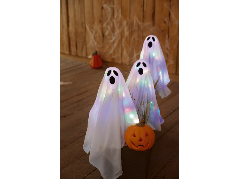 Glowing ghosts and Halloween pumpkins on a wooden background