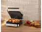 Grilled sandwiches in a sandwich maker with fresh ingredients on the side