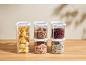 Clear storage containers with pasta, lentils, beans, muesli, and rice on a wooden table.