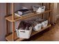 Wooden shelving unit with white storage boxes, books, and throws.
