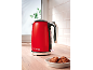 Red electric kettle with the inscription '1973' on a wooden countertop with cookies.
