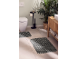 Bathroom with two striped bath mats, toilet, plant, and wooden vanity.
