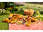 Picnic with a variety of pastries, berries, and drinks on a red checkered blanket.