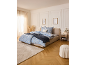 Bedroom with blue floral bedding, beige bed frame, and wooden floor.