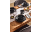 Wooden table set with matte black dinnerware, cutlery, and a charcuterie board.