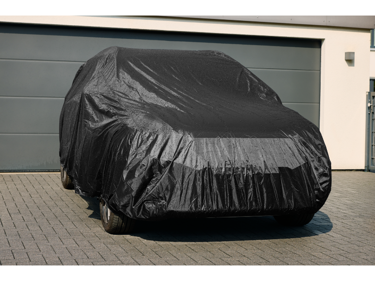Black car cover covering a car in front of a garage