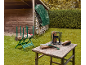 Wood sawhorse and log splitter in a garden, with a saw and wood on a table.