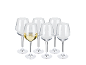 Six wine glasses, one filled with white wine, on a black background.